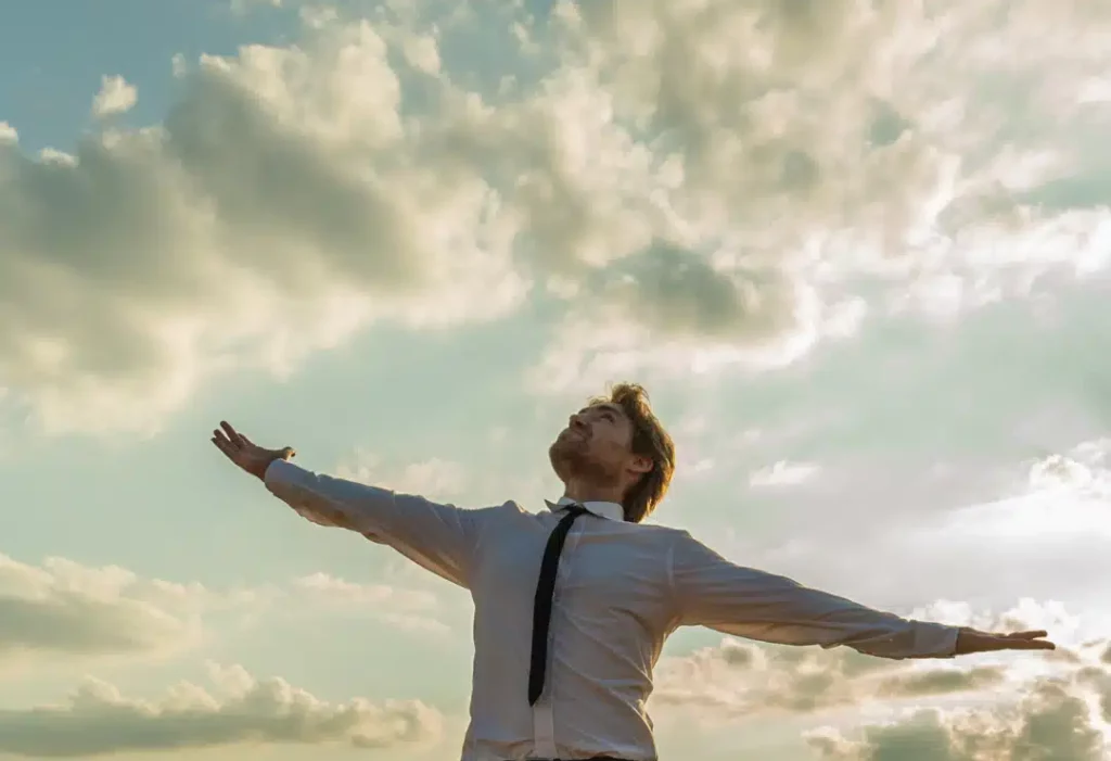 Un cadre avec les bras écartés face au ciel, symbolisant l'aspiration à l'autonomie, la compétence et un meilleur environnement de travail dans le cadre de la QVT.