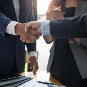 Deux professionnels se serrent la main dans un bureau, symbolisant le pardon et la collaboration en entreprise.