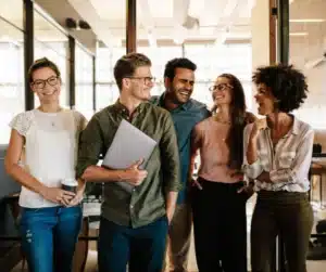 Groupe de collègues souriants discutant dans un bureau lumineux.