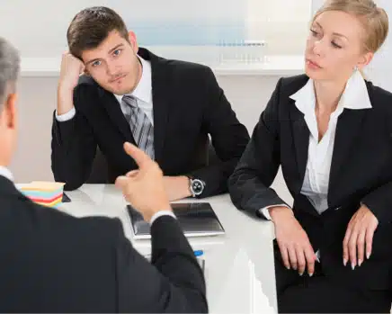 Deux professionnels en discussion sérieuse avec un superviseur dans un bureau.