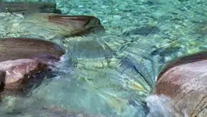 Eau fluide qui s’écoule entre les roches, symbole du passage du décalage à l’alignement authentique au travail
